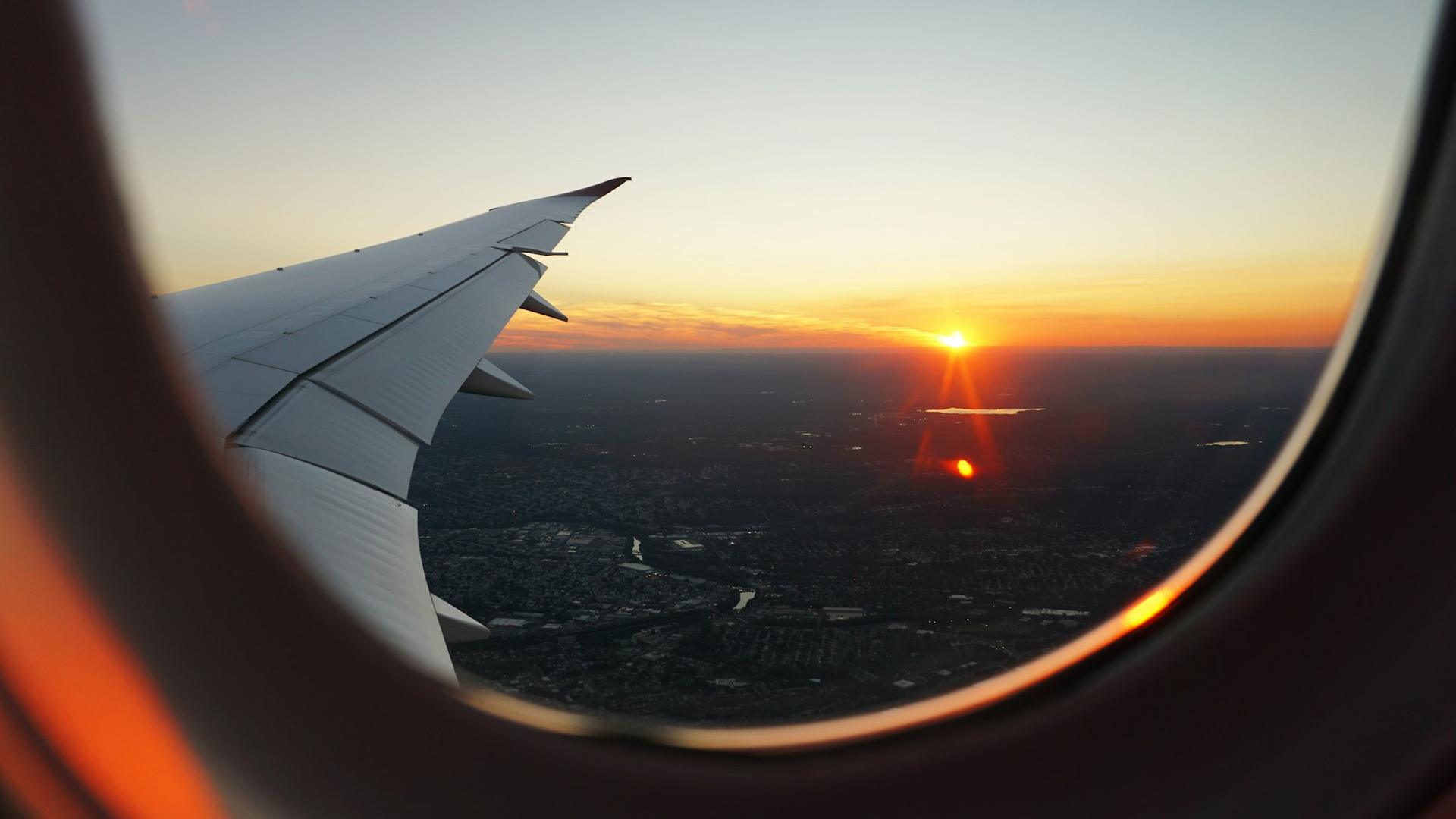 Aircraft wing at sunset through a window