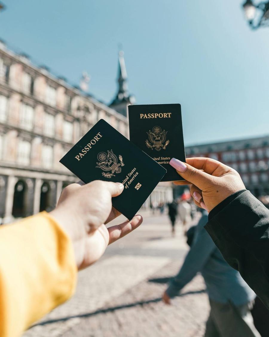 Two travellers holding up their passports